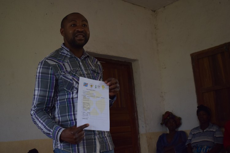 Rafiki Ise Kalulu, spécialiste de la chaîne de valeur café à notre antenne de Butembo, montrant la fiche d'évaluation aux pépiniéristes photos: Merveille Saliboko
